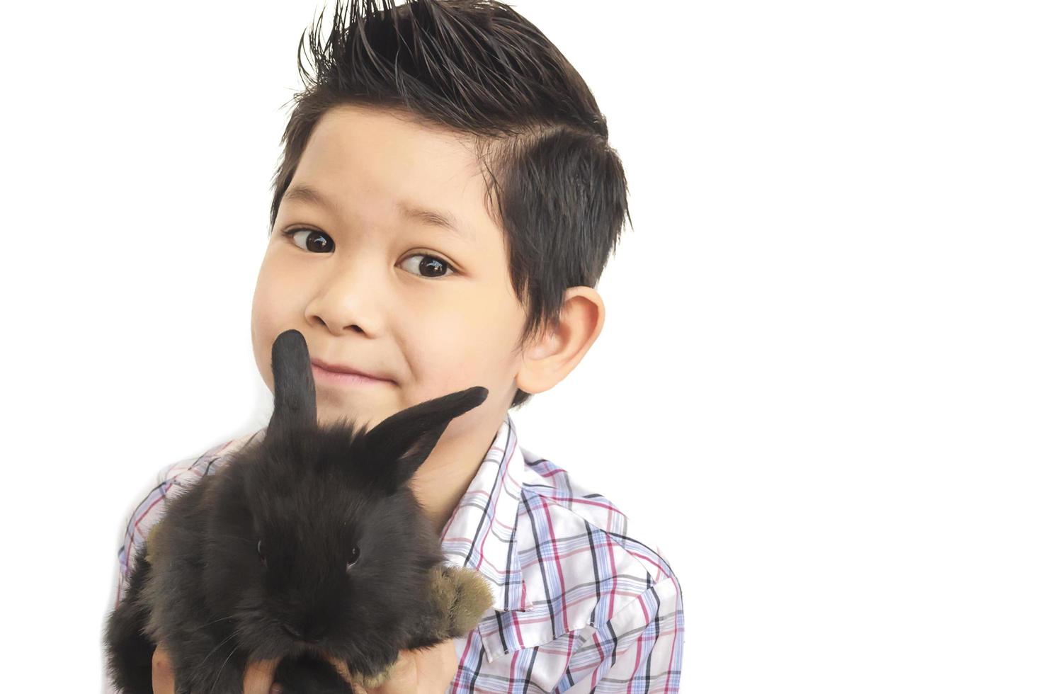 niño asiático jugando con un encantador conejo bebé aislado sobre blanco foto