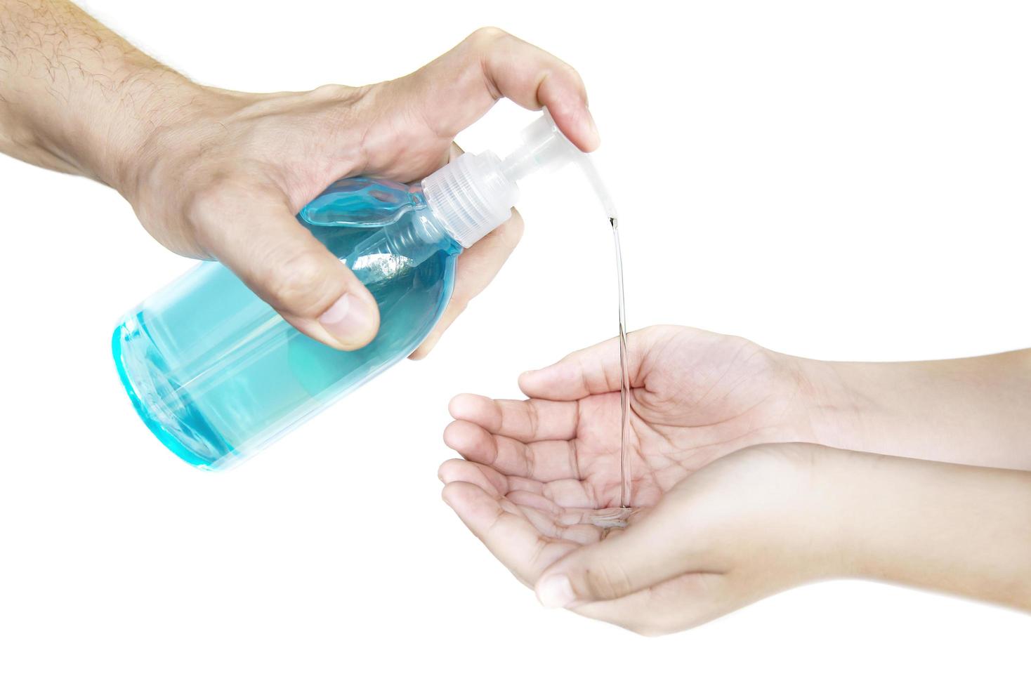 Closeup of father hand pushing alcohol sanitizer gel pump dispenser to son hand isolated over white background - people with alcohol sanitizer prevent bacteria and COVID-19 virus protection concept. photo