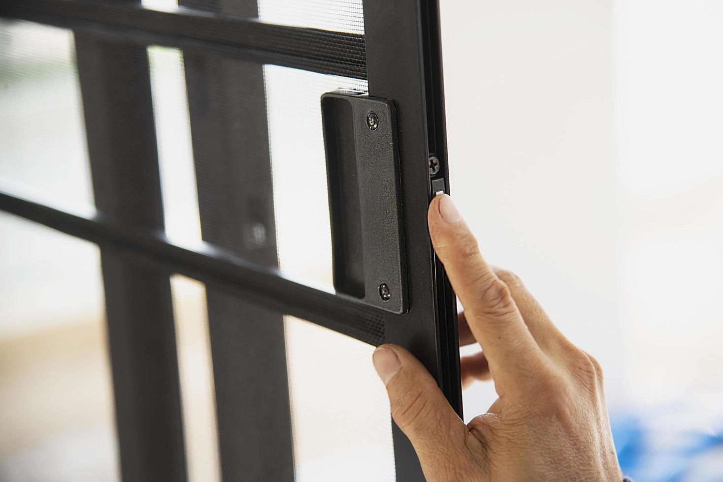 Man doing aluminum frame with glasses and wire screen door and window installation work in construction site photo