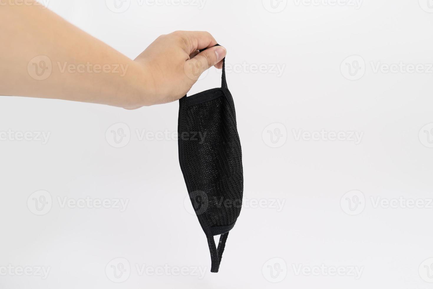 Asian man hand holds black cloth mask in studio light on white background. photo