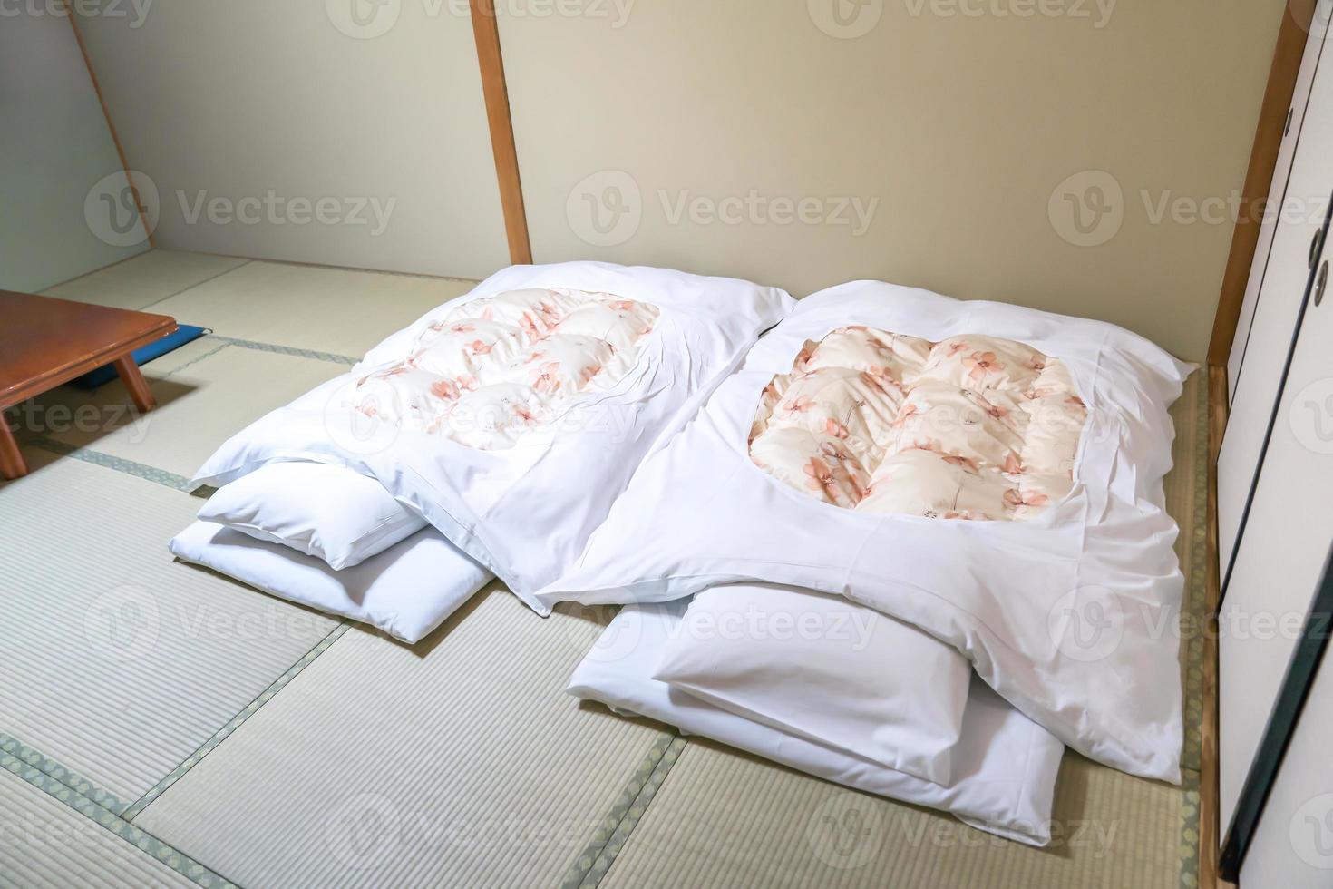 futón un colchón acolchado japonés enrollado en el suelo tatami para usar como cama, estilo japonés. foto