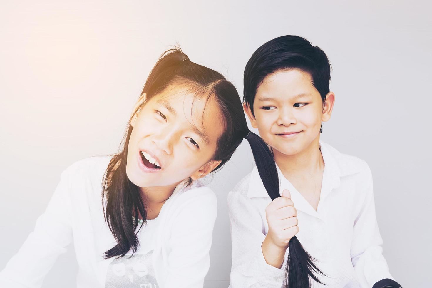 Vintage photo of lovely Asian couple school kids playing together, 7 and 10 years old, over gray background