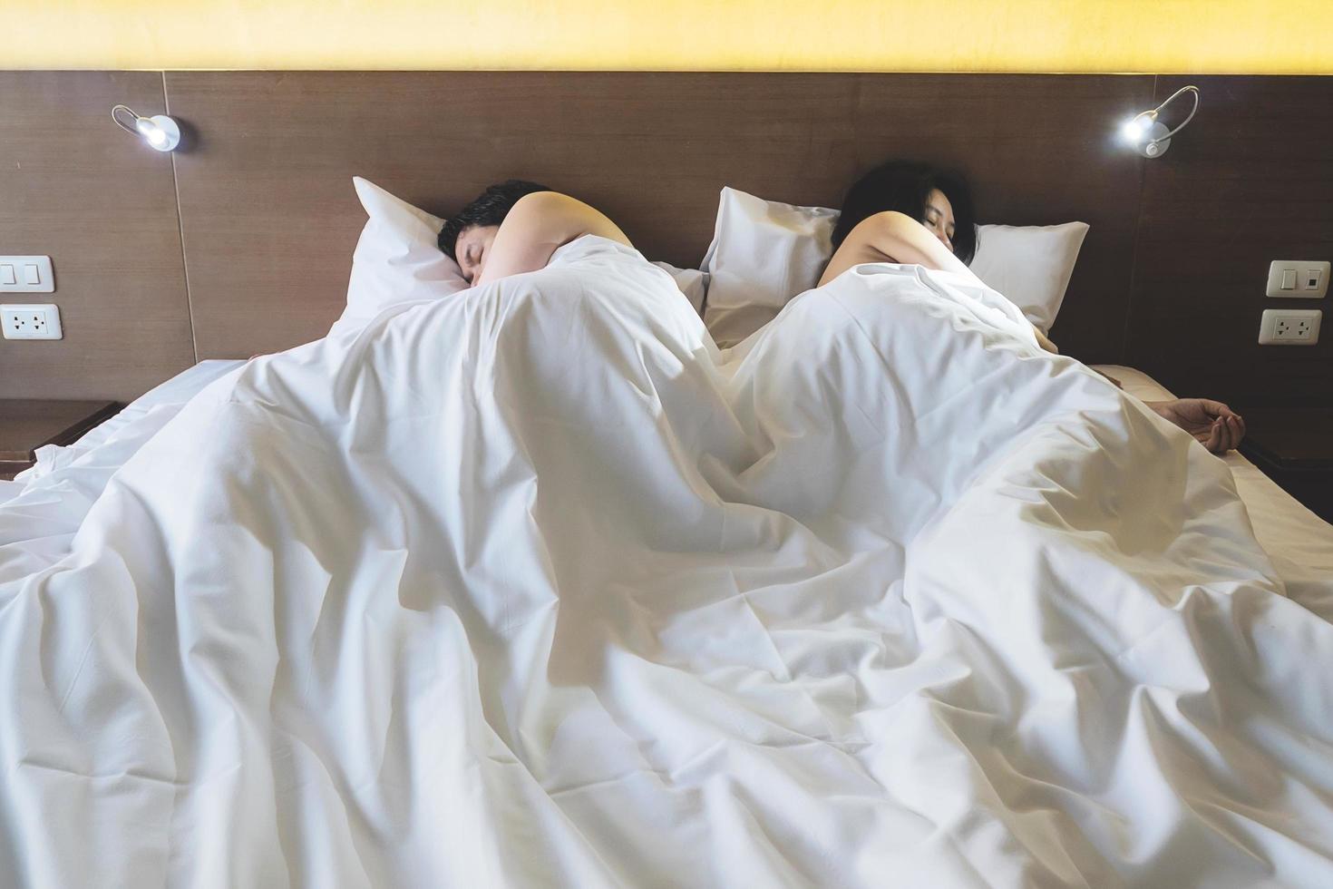 Asian couple lying on bed boring each other photo