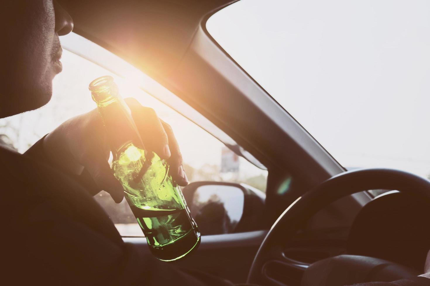 Man drinking beer while driving a car photo