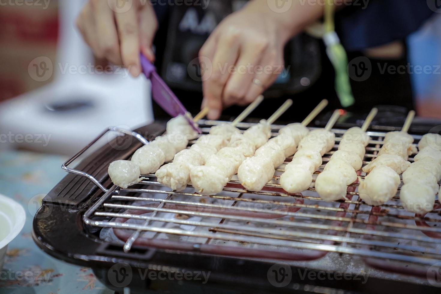 woman hand slide meat ball that was grilled on the grilling machine. photo