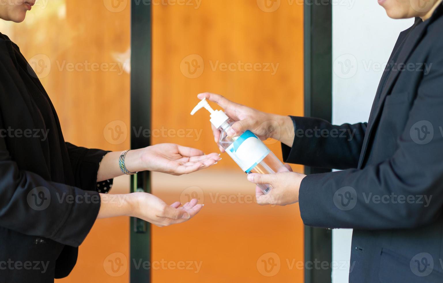 Two Asian business man and woman in black suit are washing their hands by alcohol gel before enter the meeting seminar room. photo