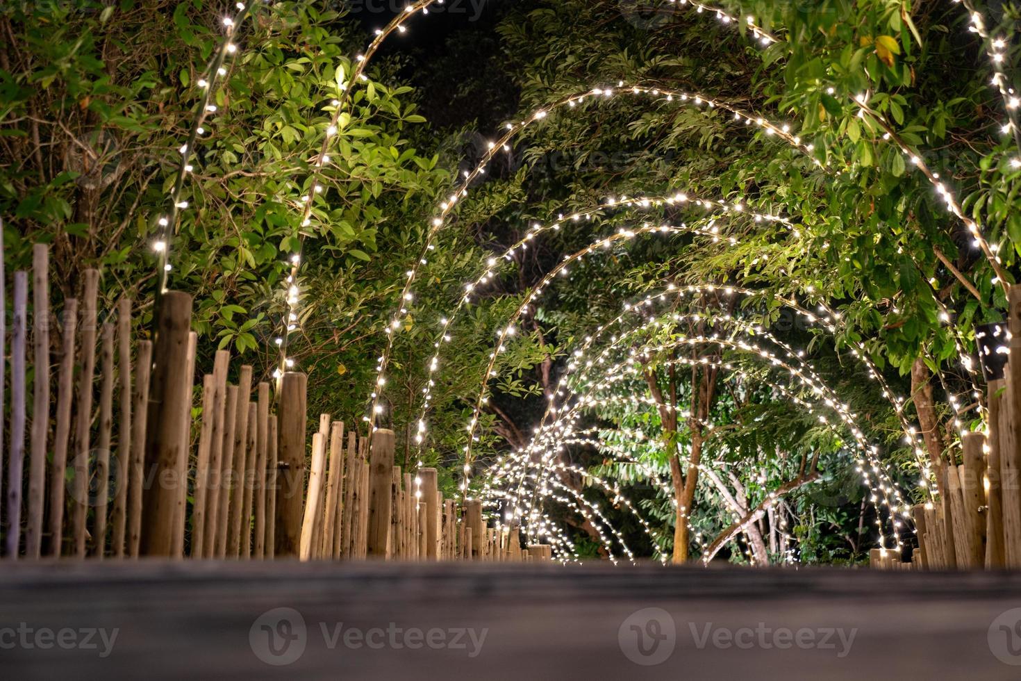 la línea de iluminación cuelga de la decoración del árbol en el concepto de cueva en la terraza de madera caminando con oscurecimiento alrededor. foto