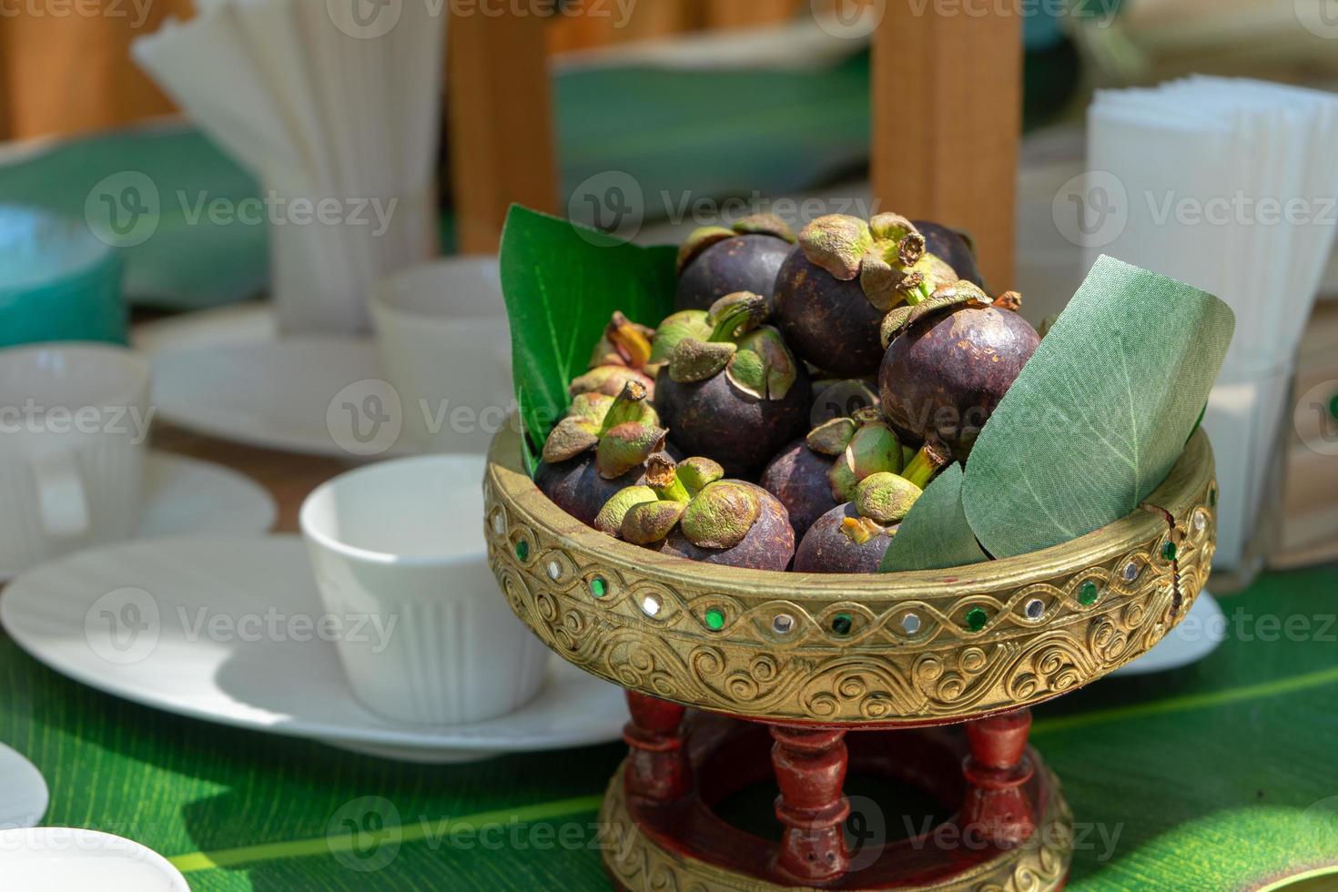 Mangosteen on the Asian Thai vintage phan or tray on the wood table. They ready to serve for seminar coffee break time. photo