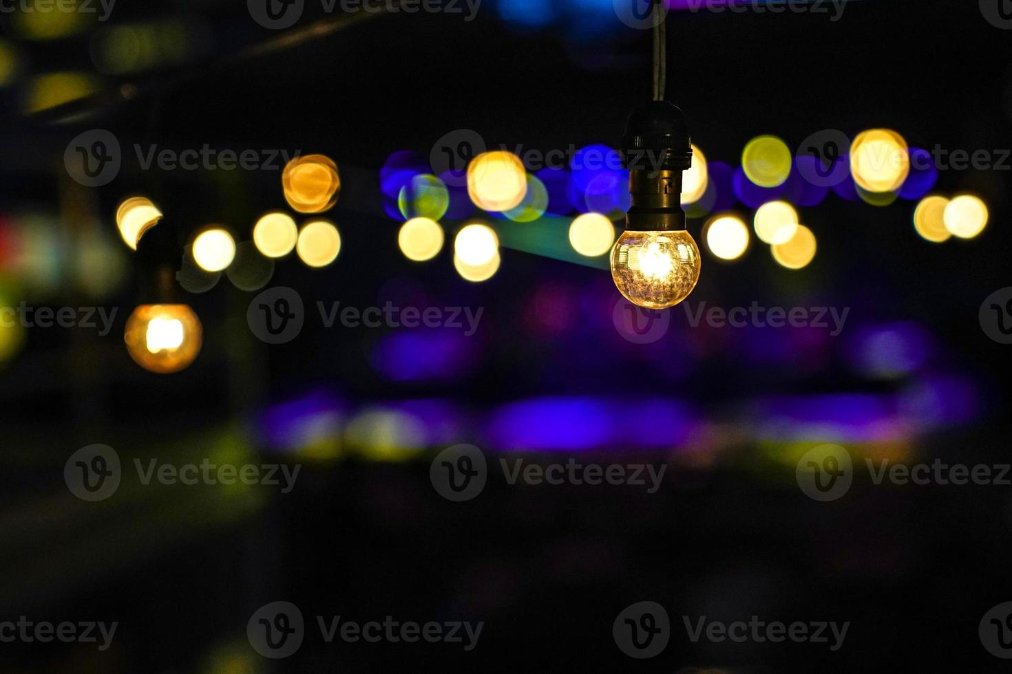 Focus on Vintage circle hanging lamp on the line with blur outdoor concert in the night bokeh background. photo