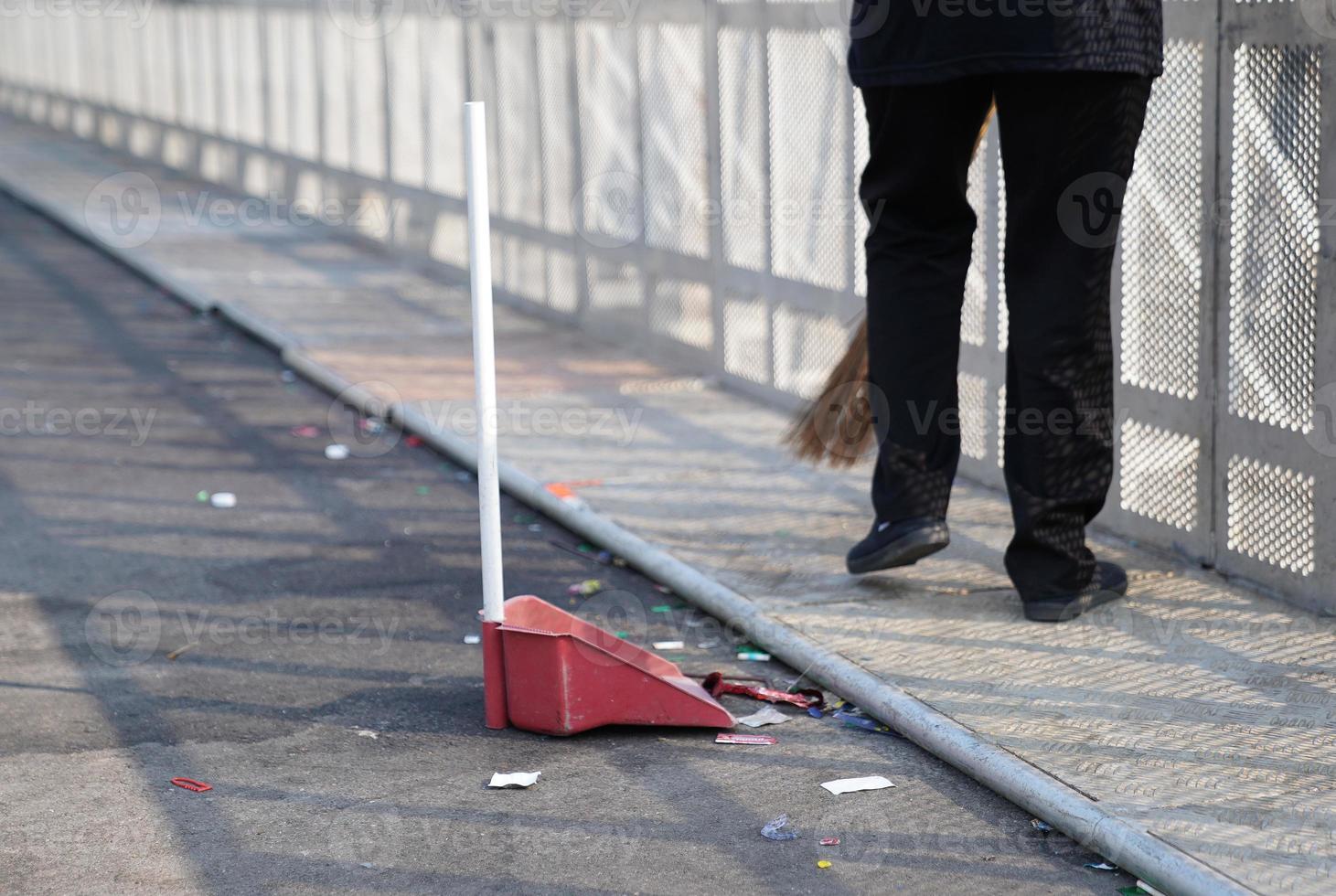 el limpiador barre la basura en una gran área de asfalto al aire libre al mediodía. foto