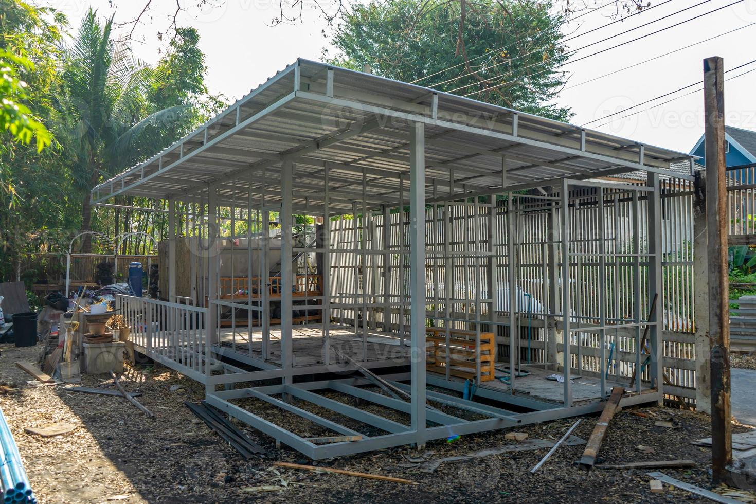 underconstruction housemaid small temporary home is made from steel pole structure without cement and brick with garden and fence around. photo