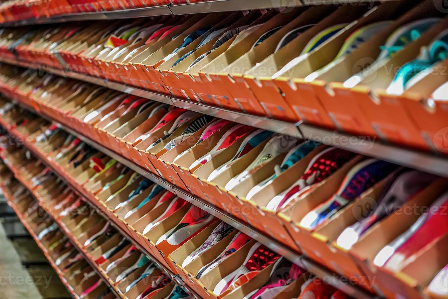 a lot of sports sneakers in the orange paper boxes on shelf ready to sales. photo