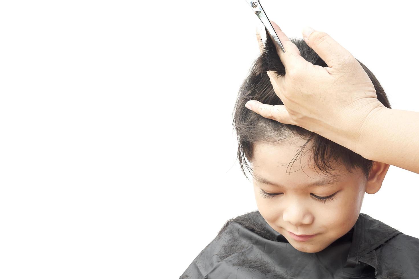 A boy is cut his hair by hair dresser isolated over white background photo