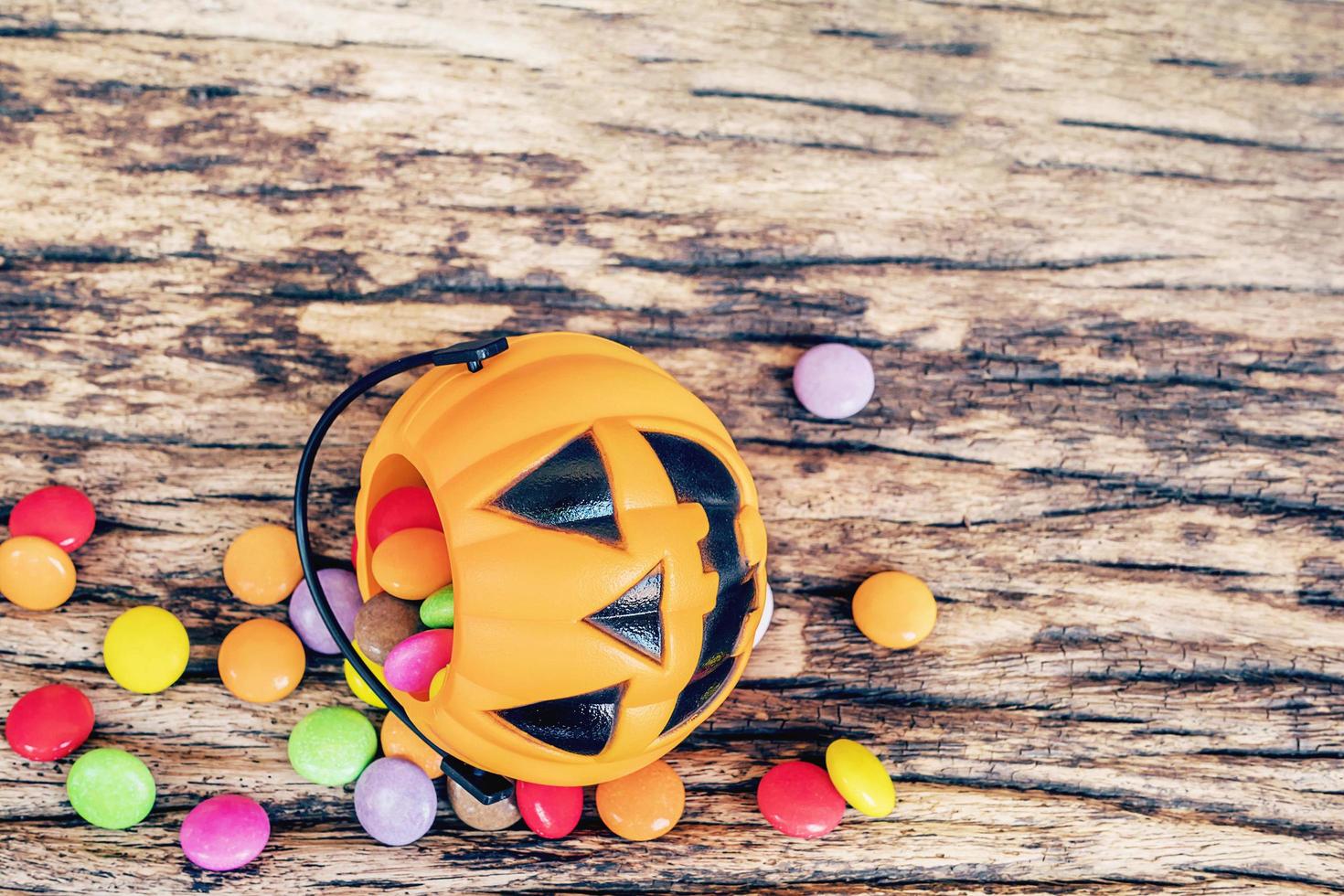 Halloween pumpkin face buckets with colorful candy inside on old wooden texture photo