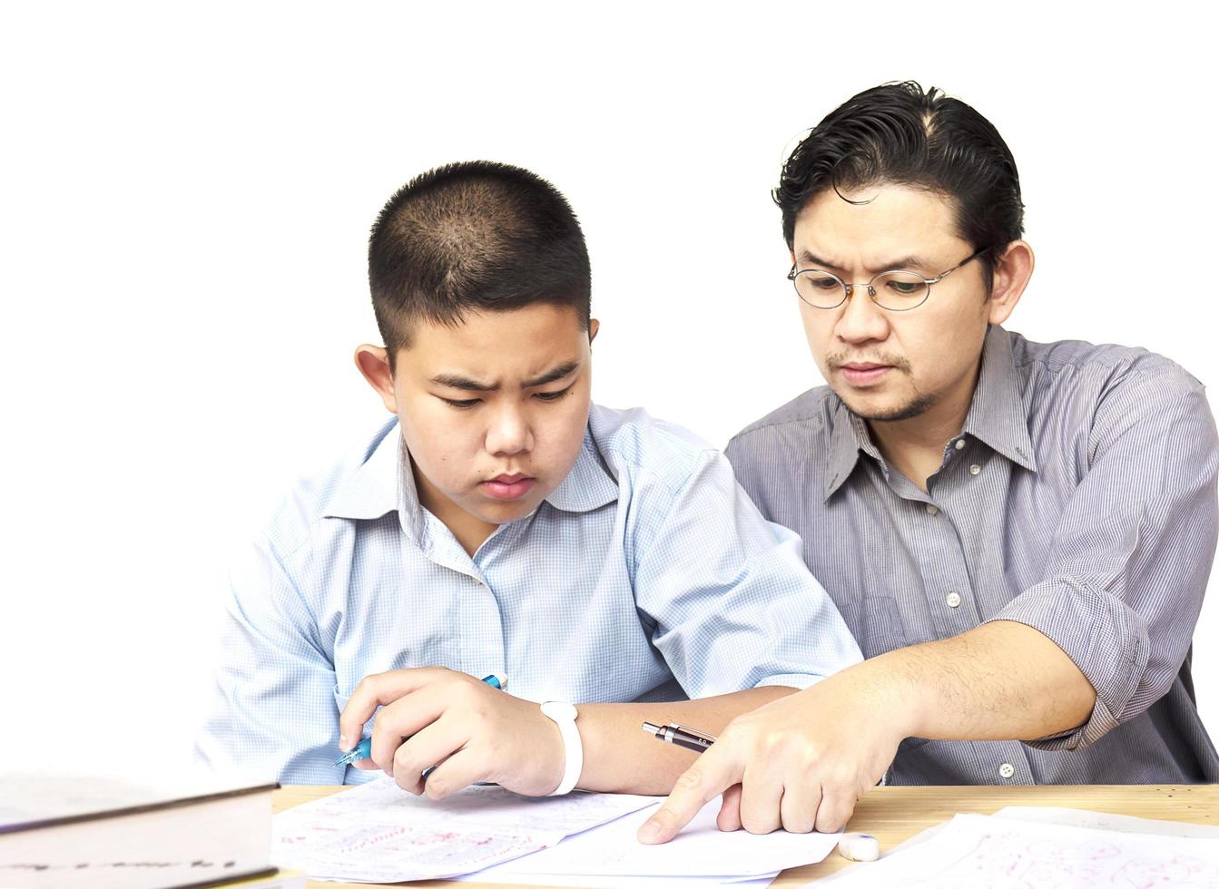 Asian father teaching homework to his 14 years son seriously photo