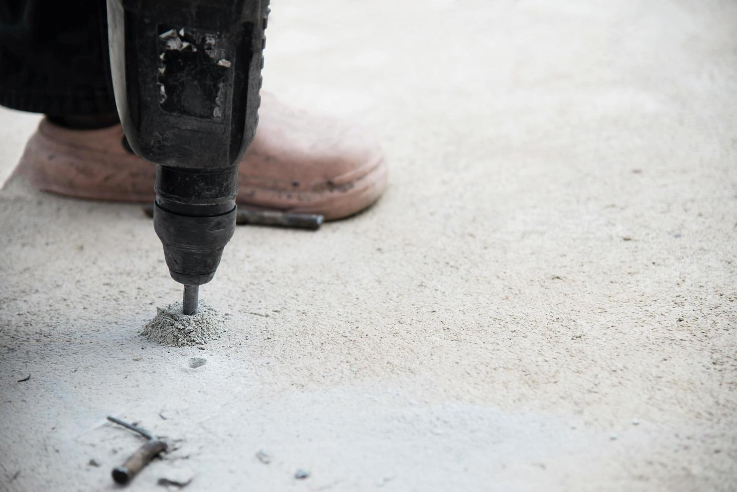 Construction worker doing his job - drilling concrete floor photo