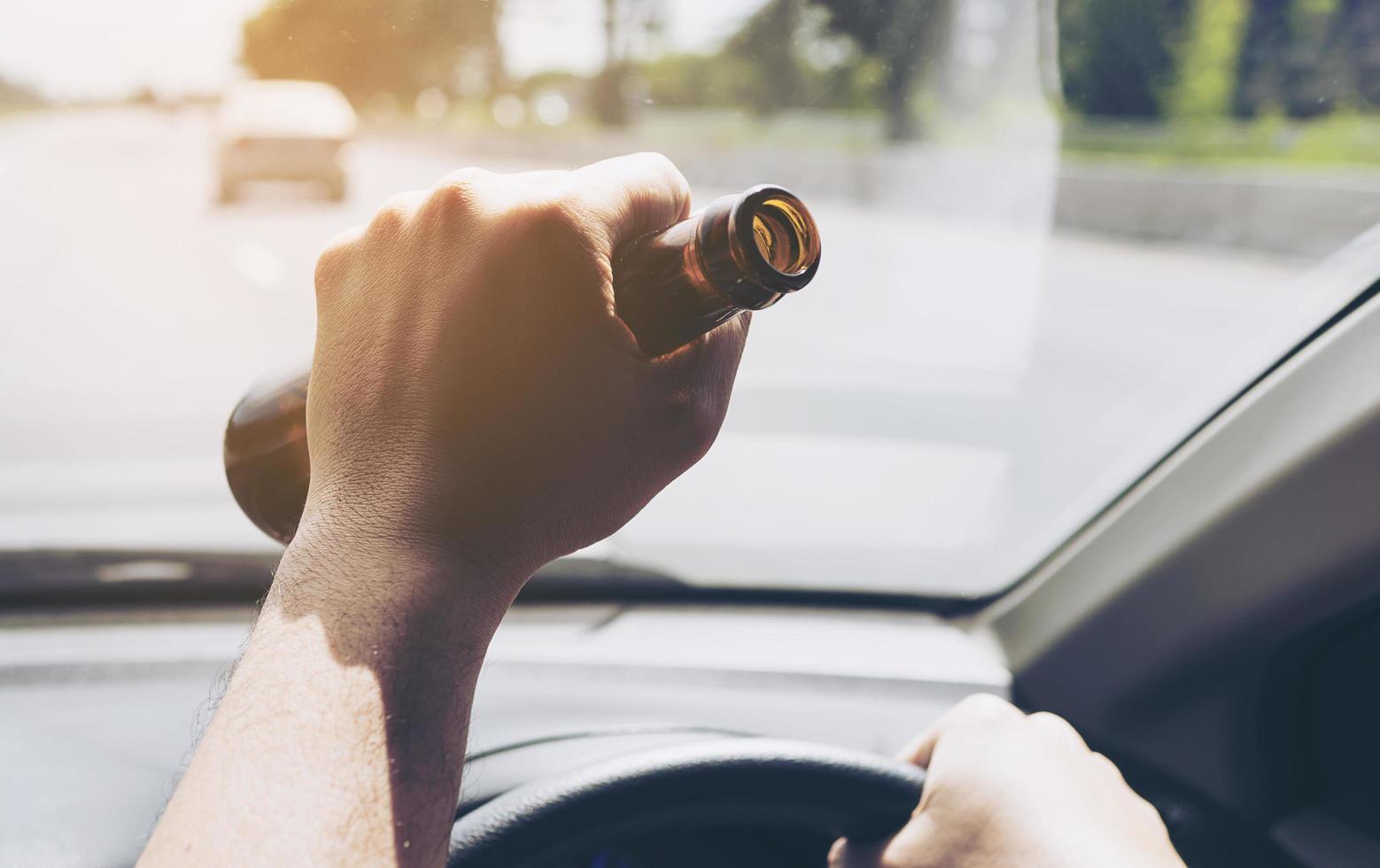 Man holding beer bottle while driving a car photo