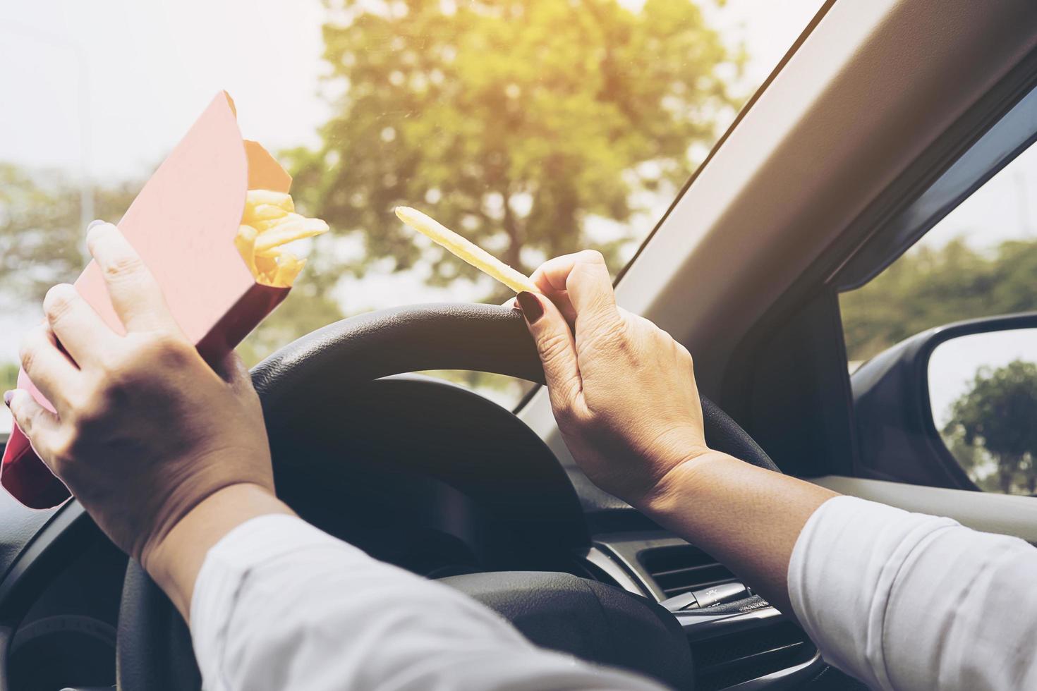 Lady eating french fries white driving car dangerously photo