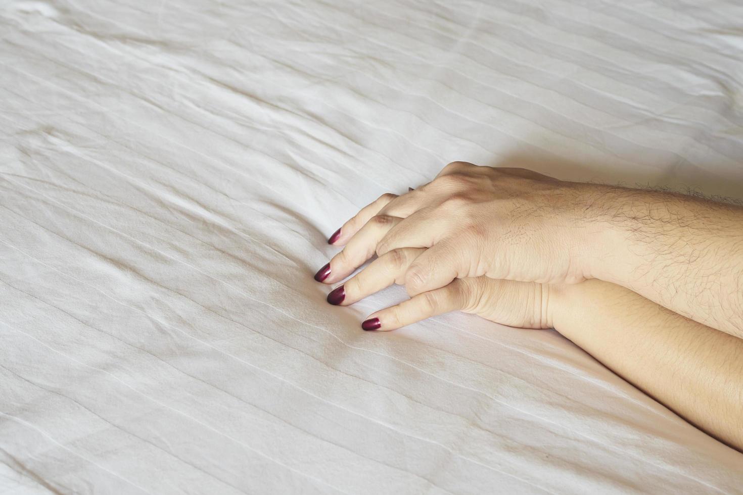 Man holding woman hand on white bed, couple sexual concept photo