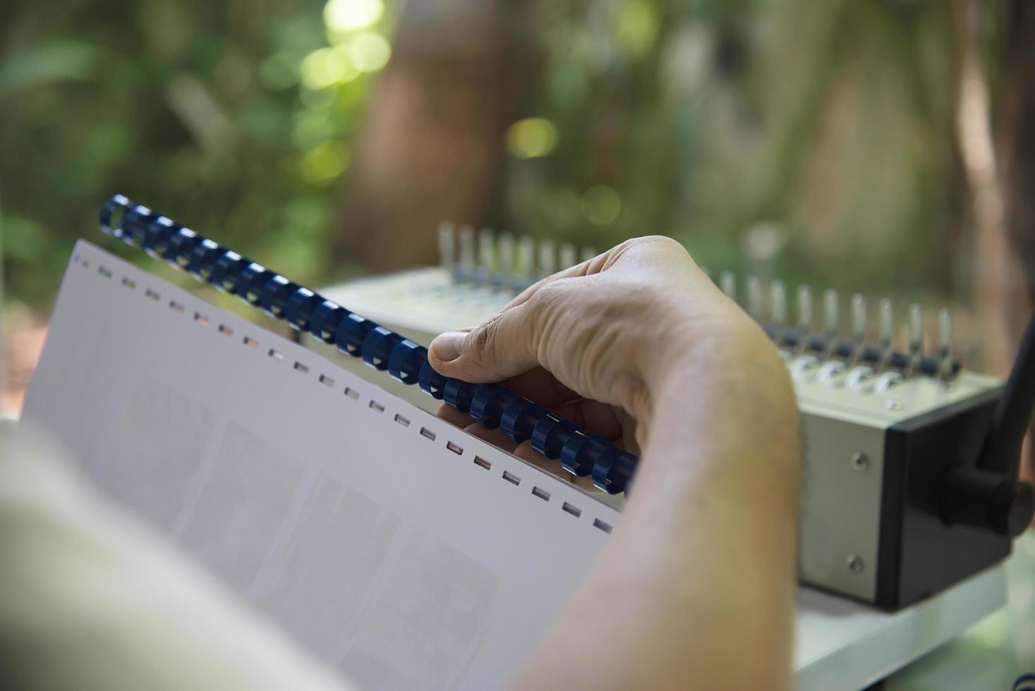 Man making report using comb binding machine - people working with stationary tools concept photo