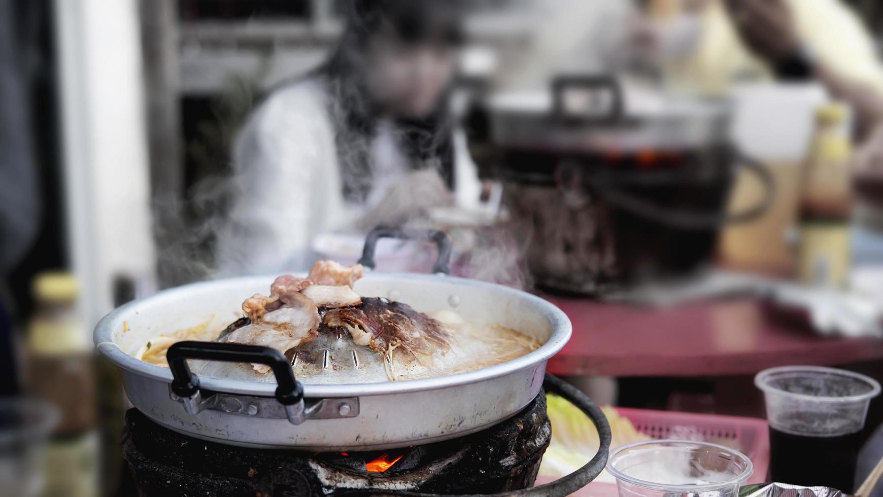 gente comiendo cerdo a la parrilla, llamado moo kratha, comida famosa para el clima frío en la naturaleza montañosa, moncham, chiang mai tailandia - famoso lugar turístico foto