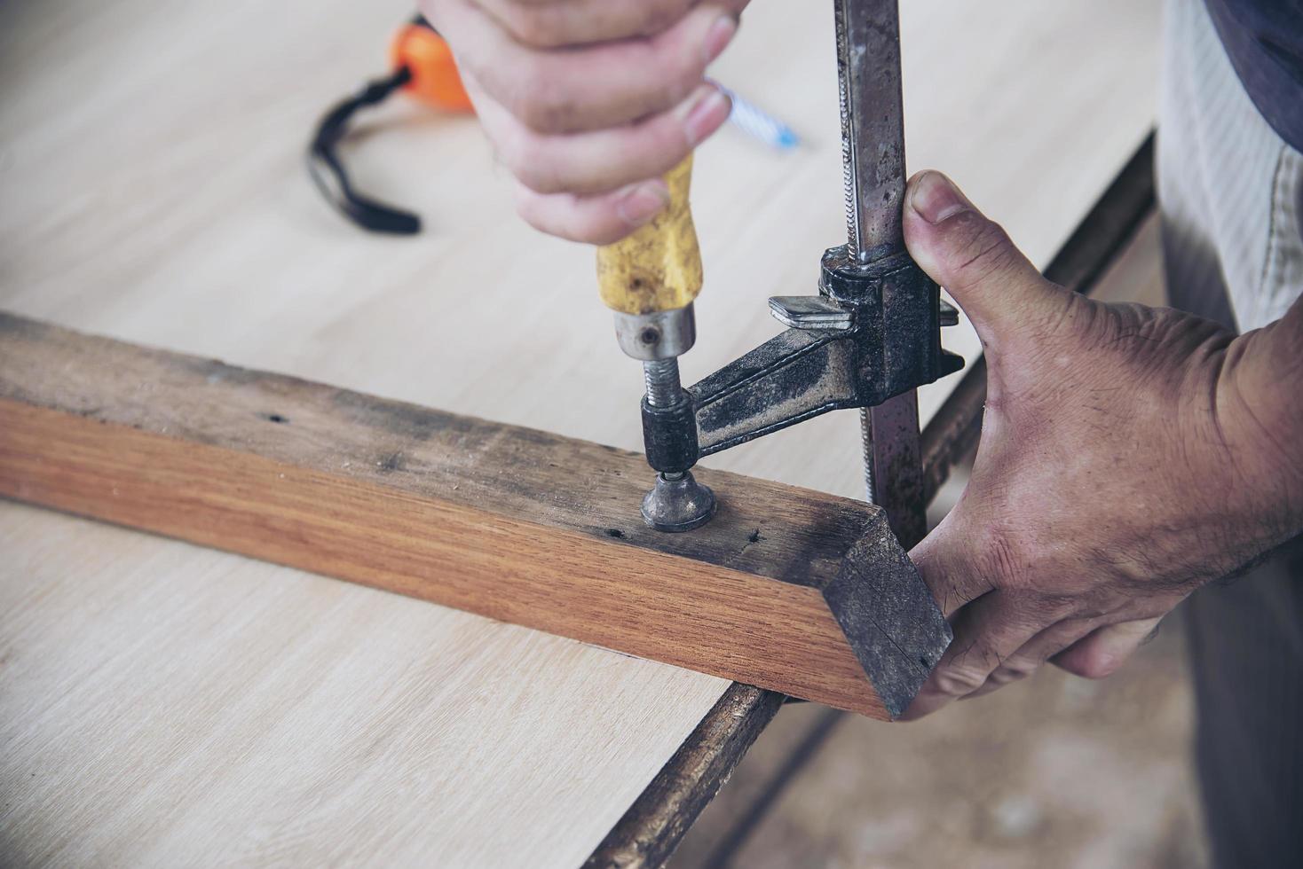 Carpenter doing wood work using clamping hand tool photo