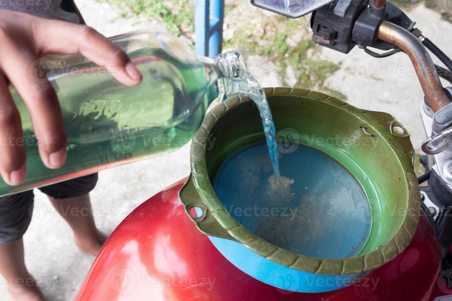 someone is pouring pertalite fuel through a glass bottle for motorcycles, gasoline sold at retail is 1 liter photo