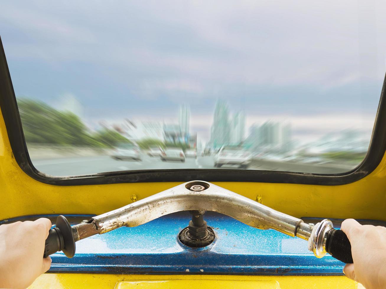 Front view of Thai Tuk Tuk looking out from inside with driver hands and road city view background photo