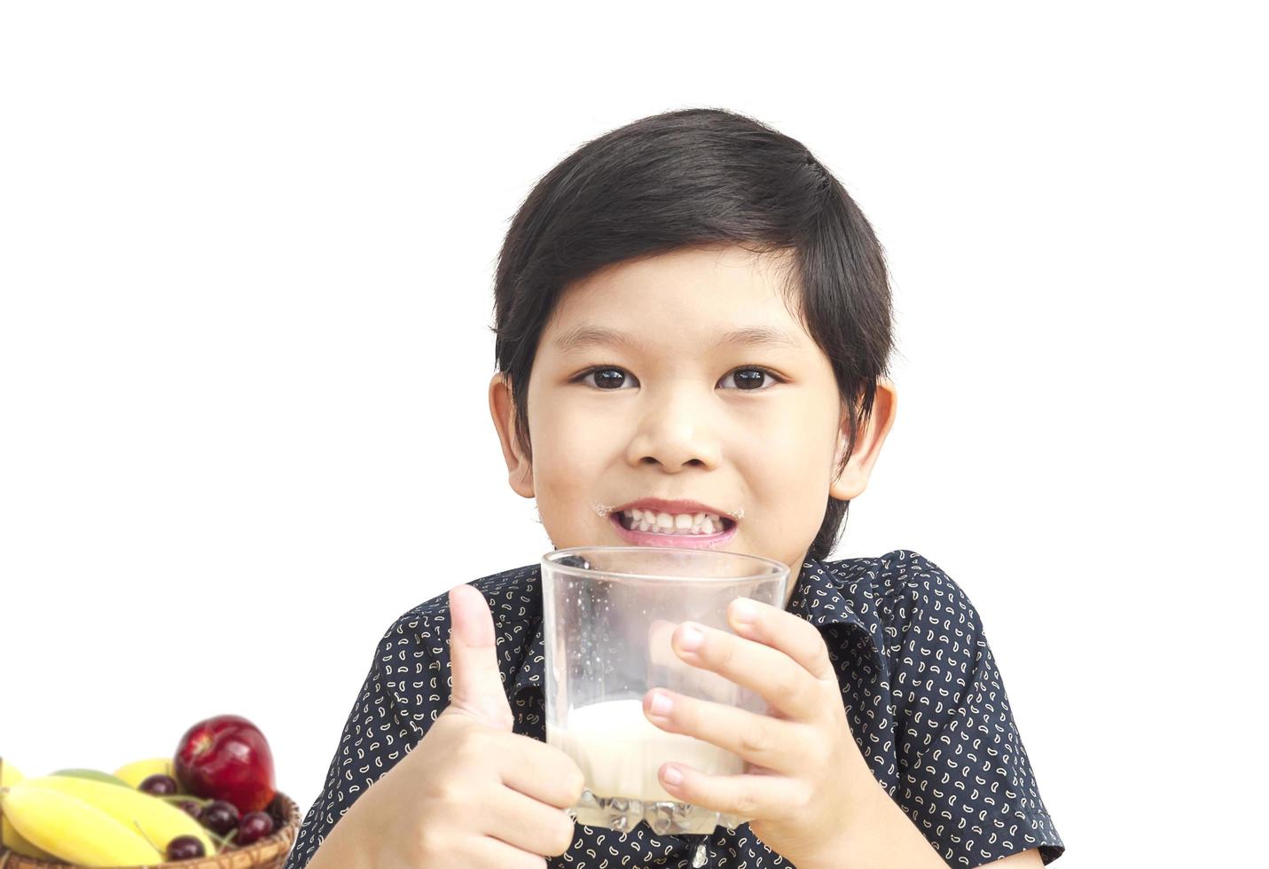 Asian boy is drinking a glass of milk over white background photo