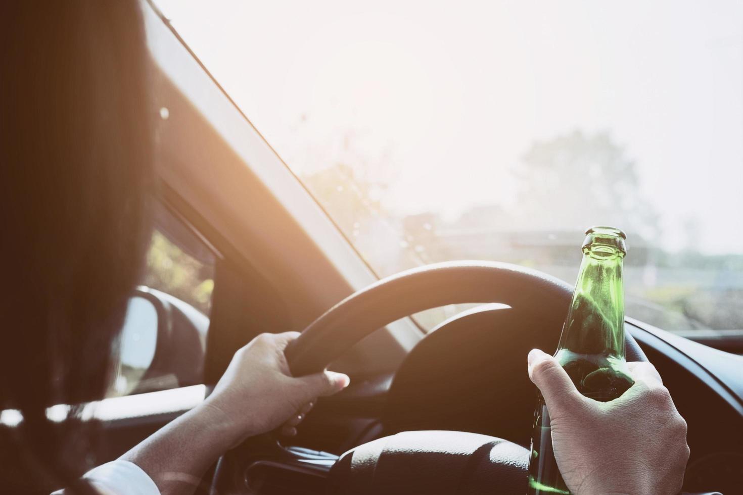 Woman holding beer bottle while driving a car photo