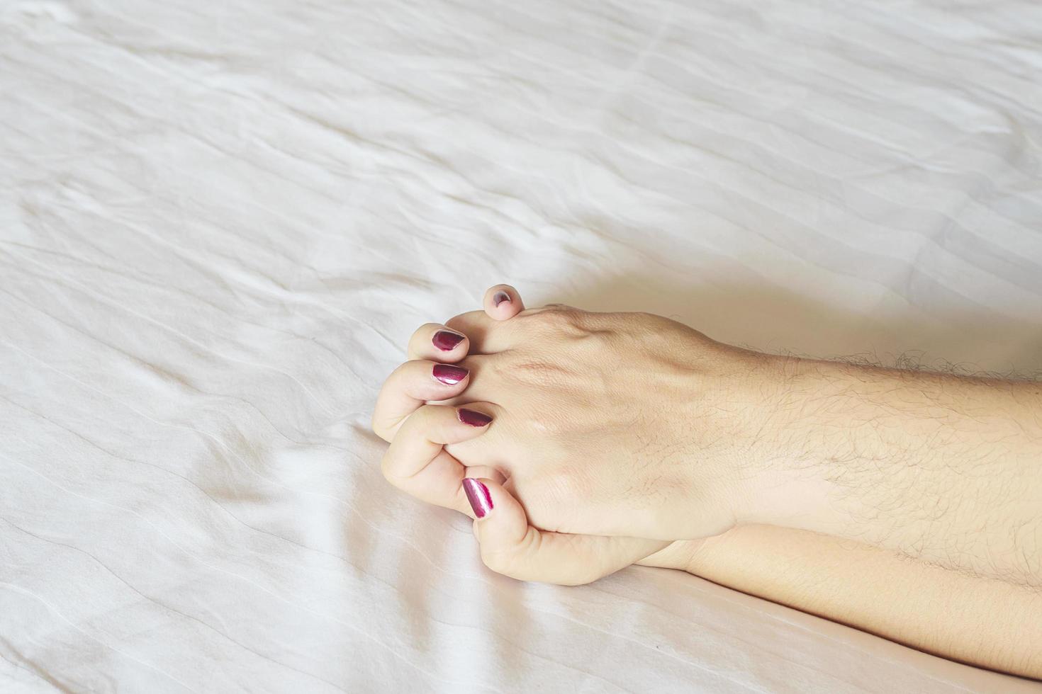 Man holding woman hand on white bed, couple sexual concept photo