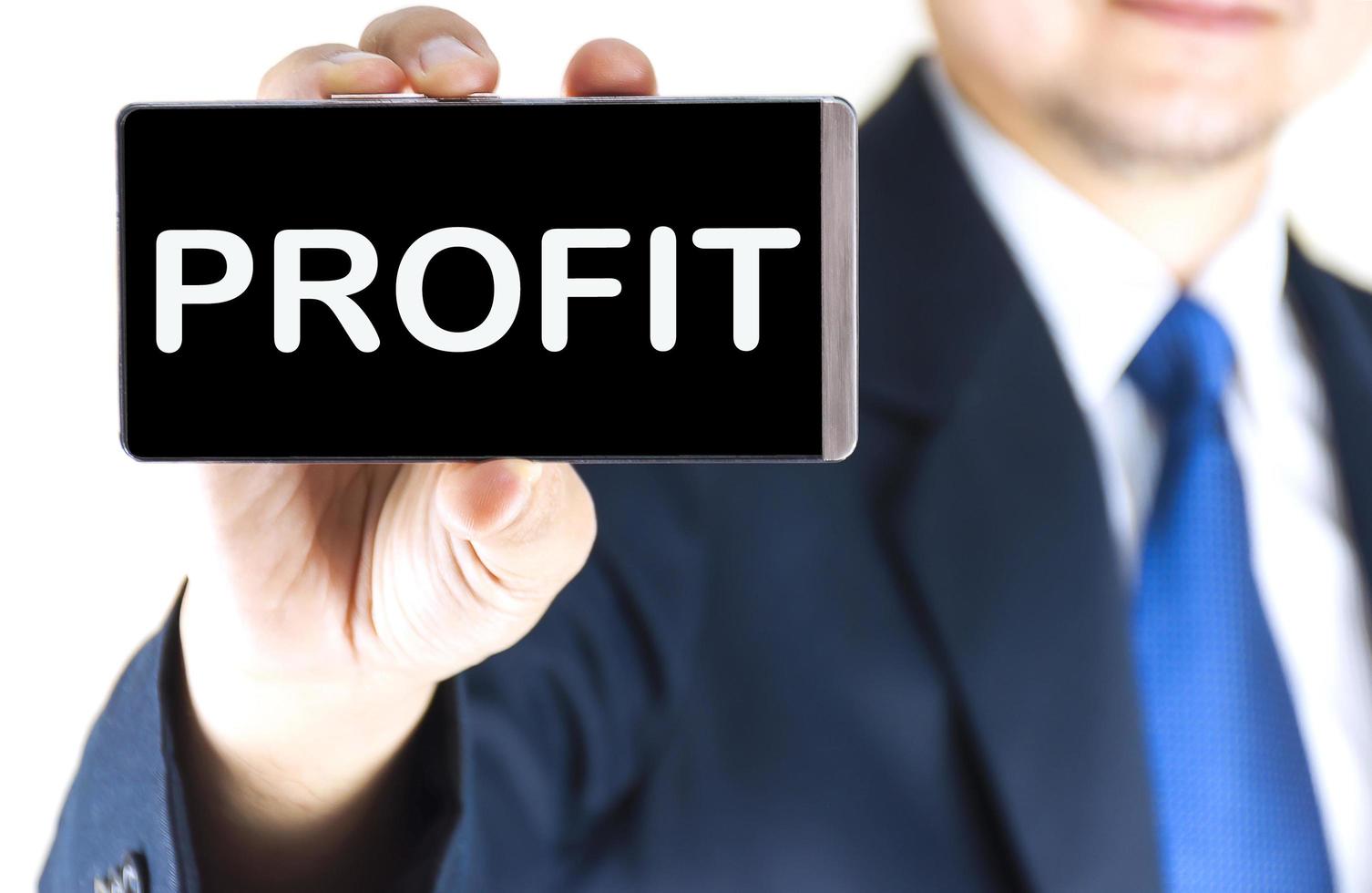 PROFIT, word on mobile phone screen in blurred young businessman hand over white background, business concept photo