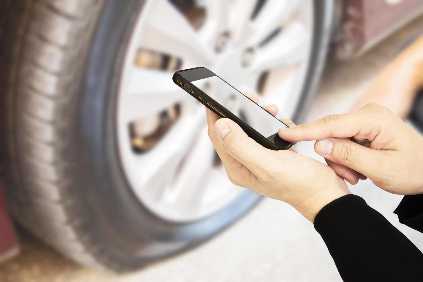 Man is using mobile phone calling somebody over car flat tire background photo
