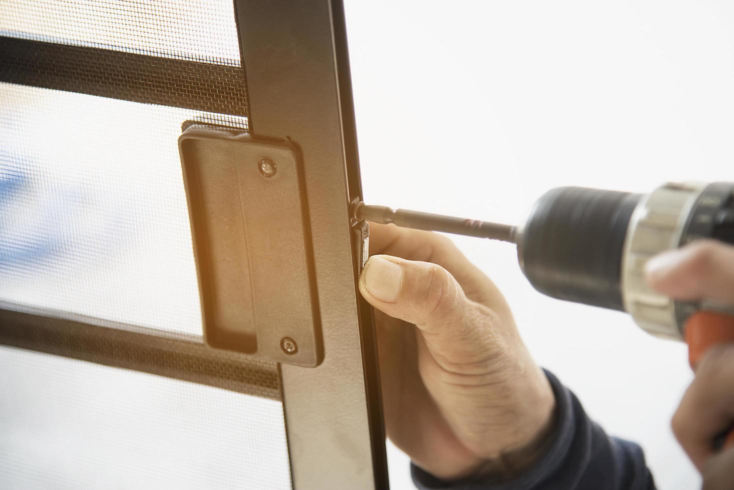 Man doing aluminum frame with glasses and wire screen door and window installation work in construction site photo