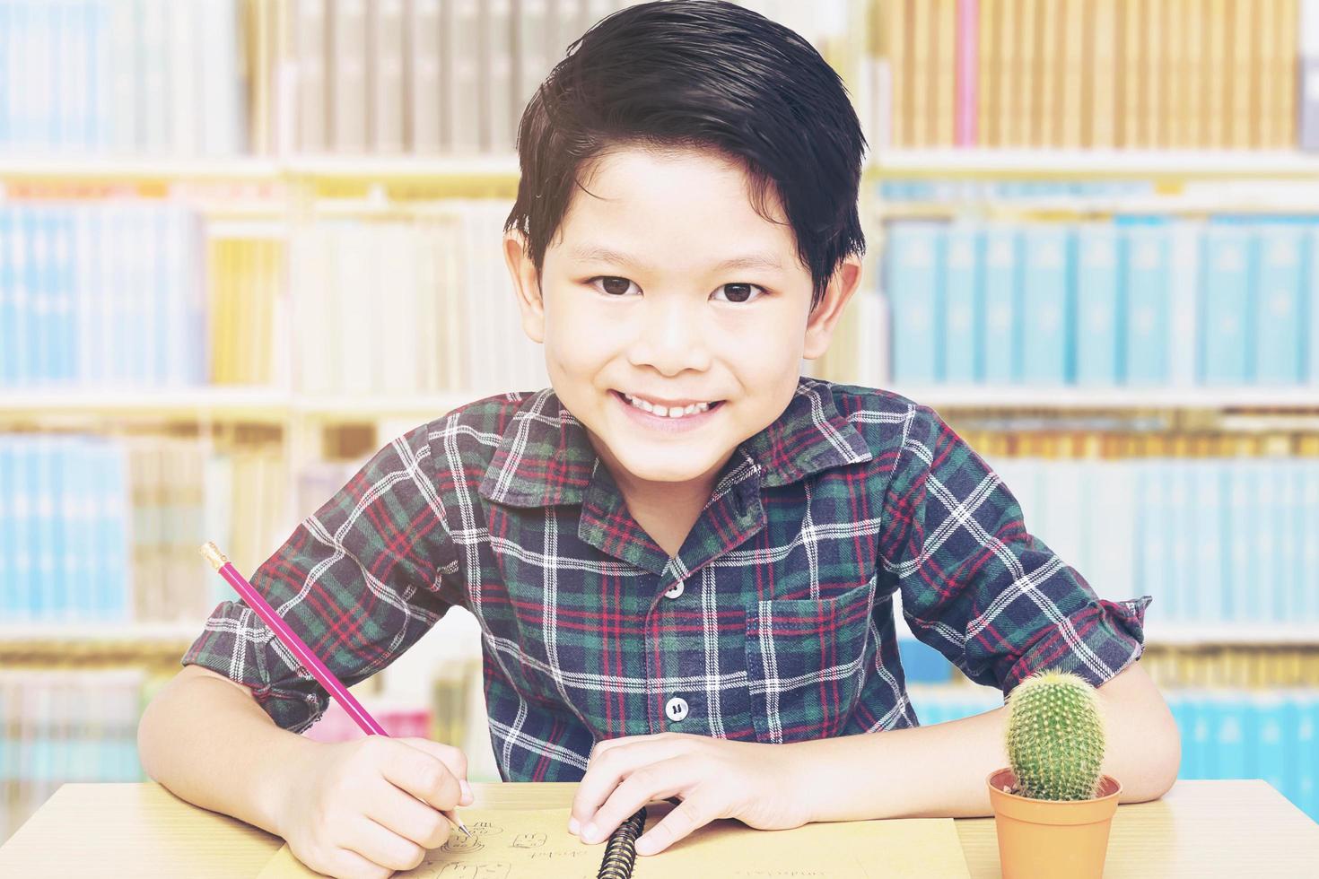 A boy is happily doing homework in a library photo