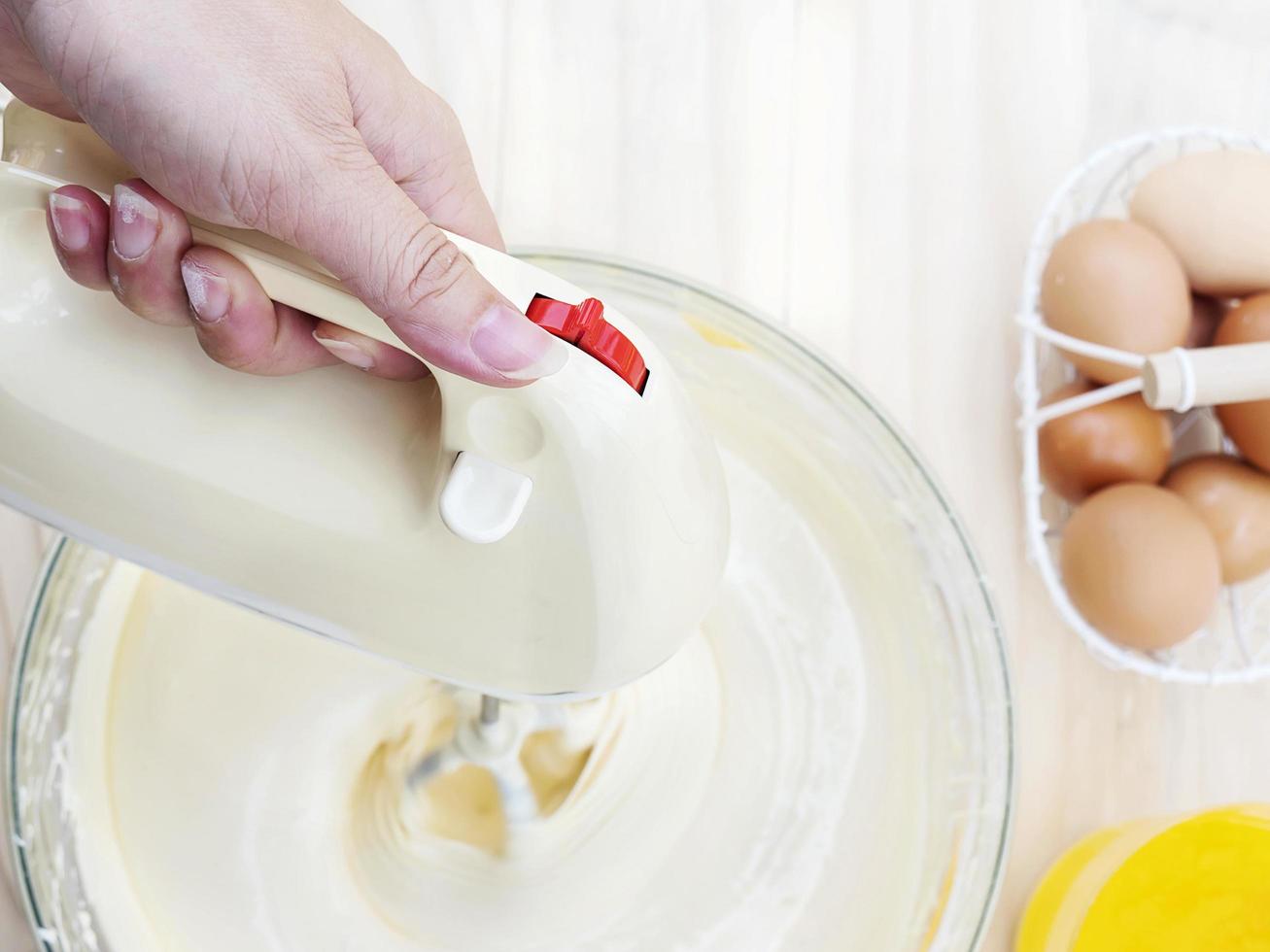 vista de juguete de la mano de la dama preparando pastel usando una máquina mezcladora manual con huevo y mantequilla foto