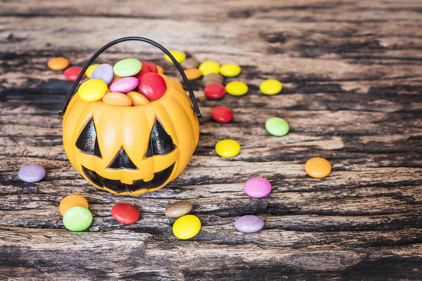 Halloween pumpkin face buckets with colorful candy inside on old wooden texture photo