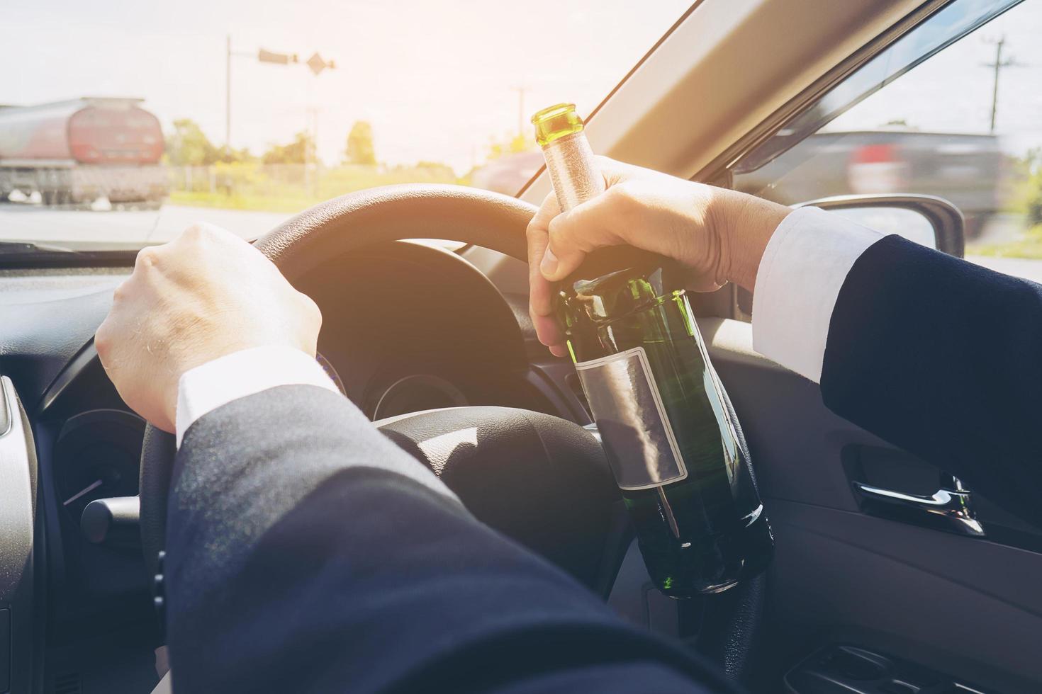 hombre sosteniendo una botella de cerveza mientras conduce un automóvil foto