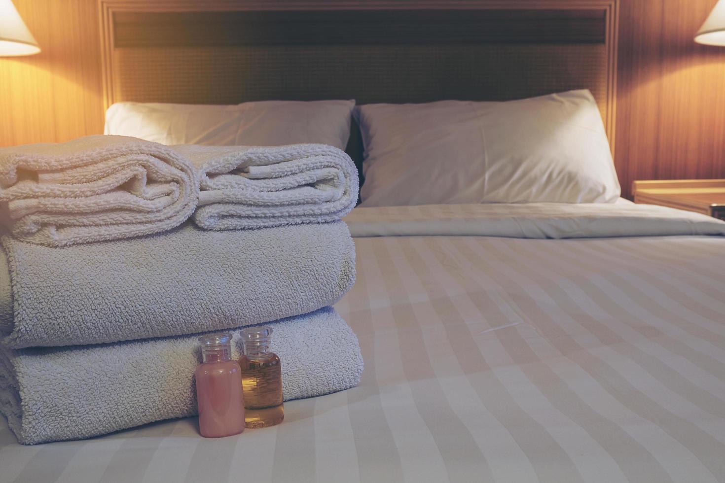 Hotel towel with shampoo and soap bottle set on white bed photo