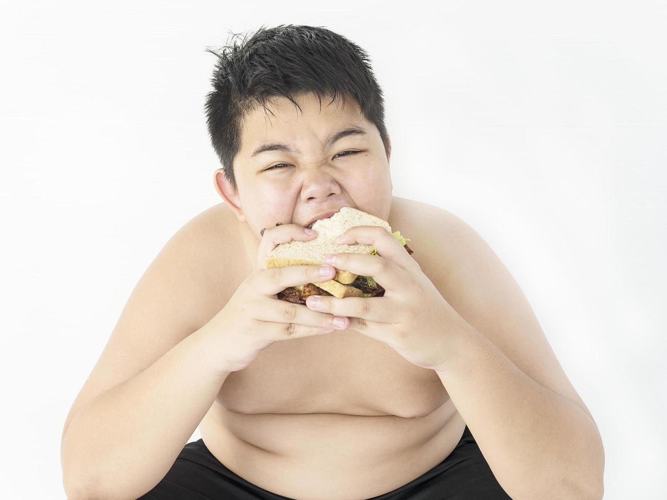 A fat boy is happily eating sandwich. photo