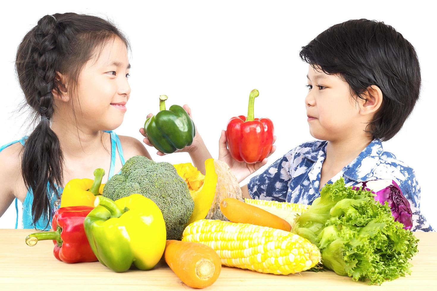 Asian boy and girl showing enjoy expression with fresh colorful vegetables isolated over white background photo
