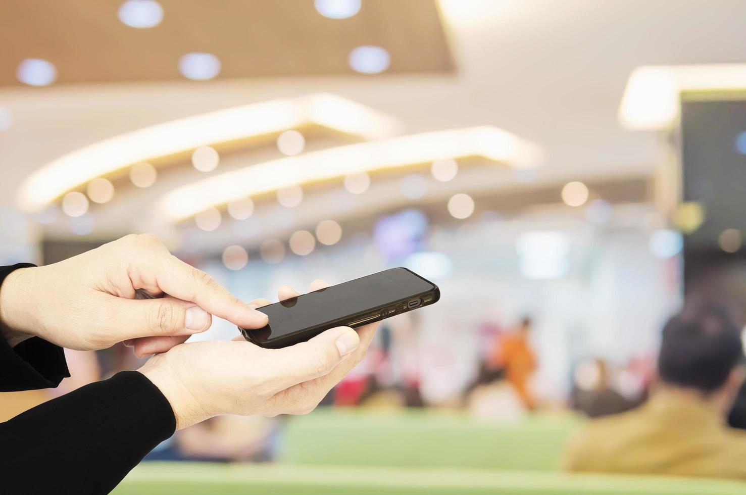 A man is using telephone over colorful blurred bokeh light in office and people background photo