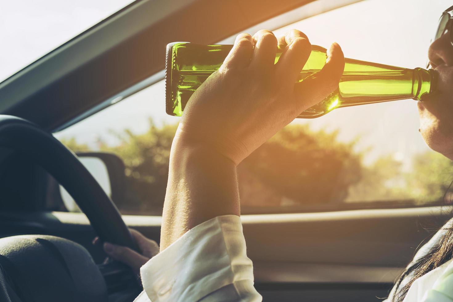 Woman drinking beer while driving a car photo