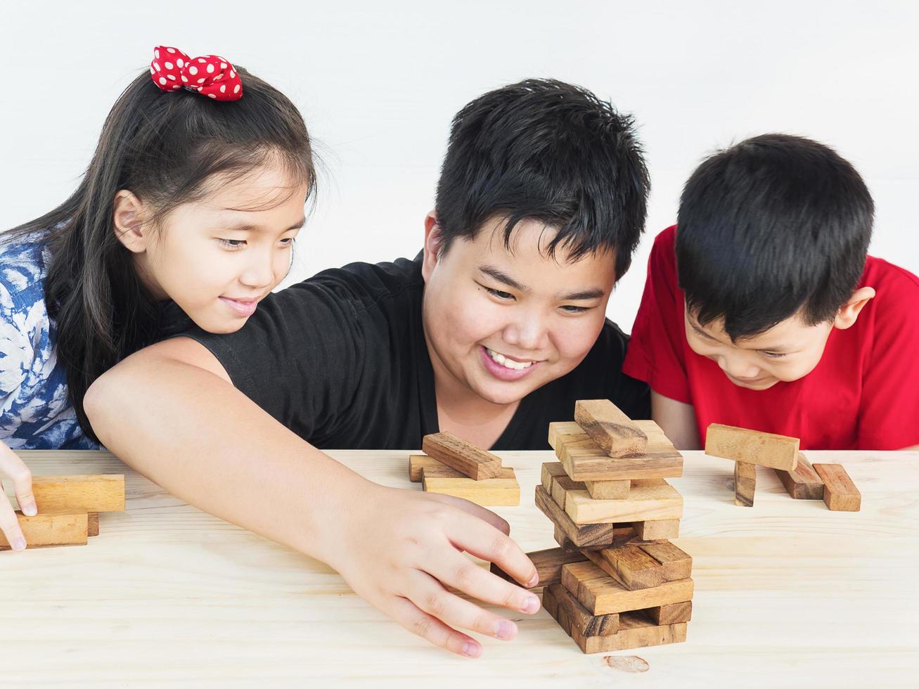 Children are playing jenga, a wood blocks tower game for practicing their physical and mental skill photo