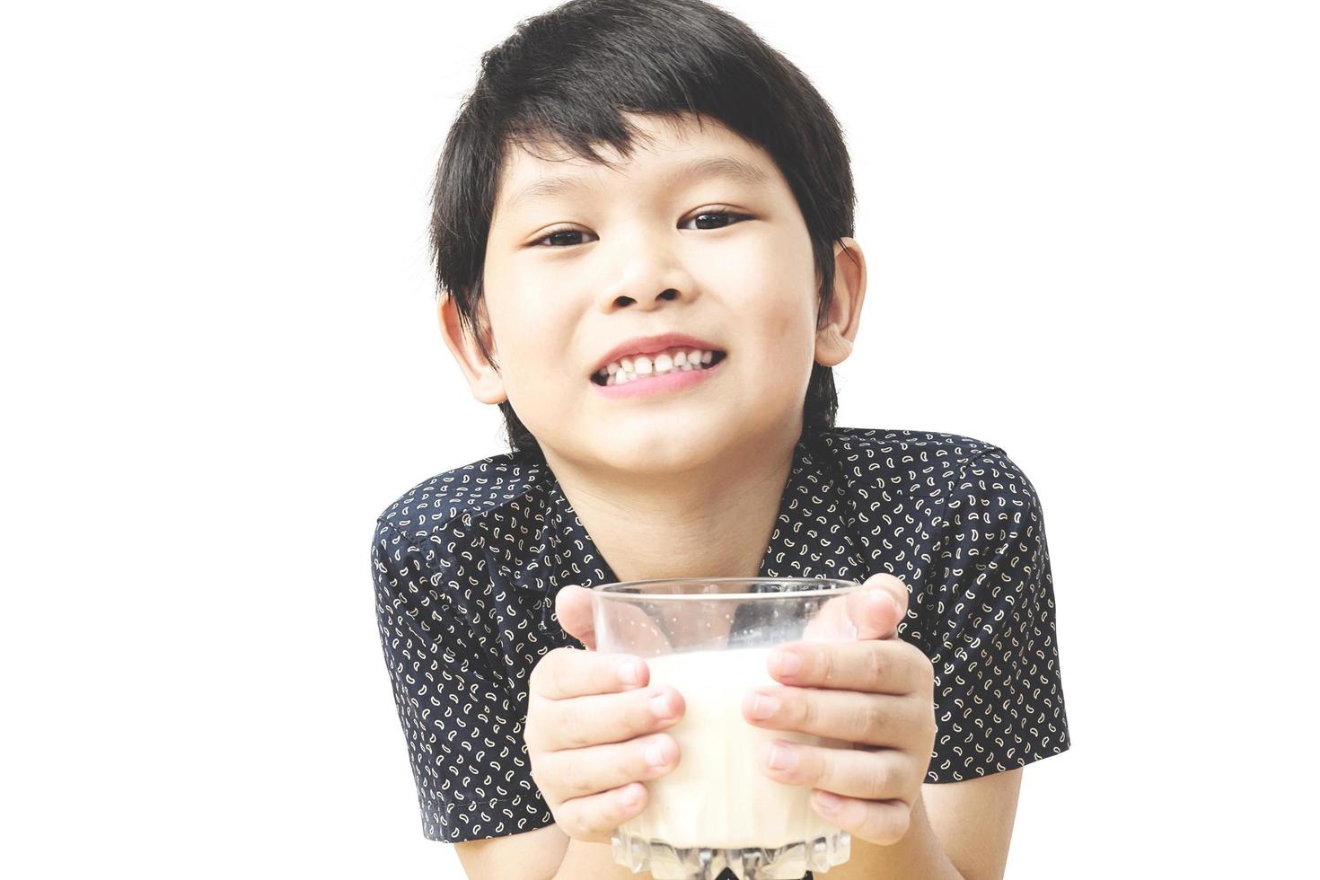 Asian boy is drinking a glass of milk over white background photo