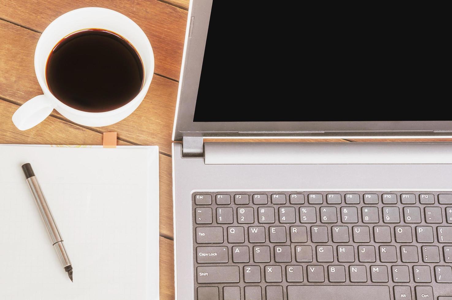 Vintage style photo of business work concept with computer laptop coffee white note paper and pen on wooden table