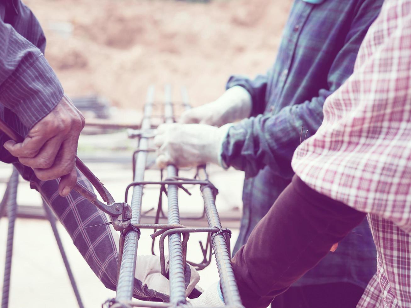 Vintage style photo of construction workers are installing steel rods in reinforced concrete beam