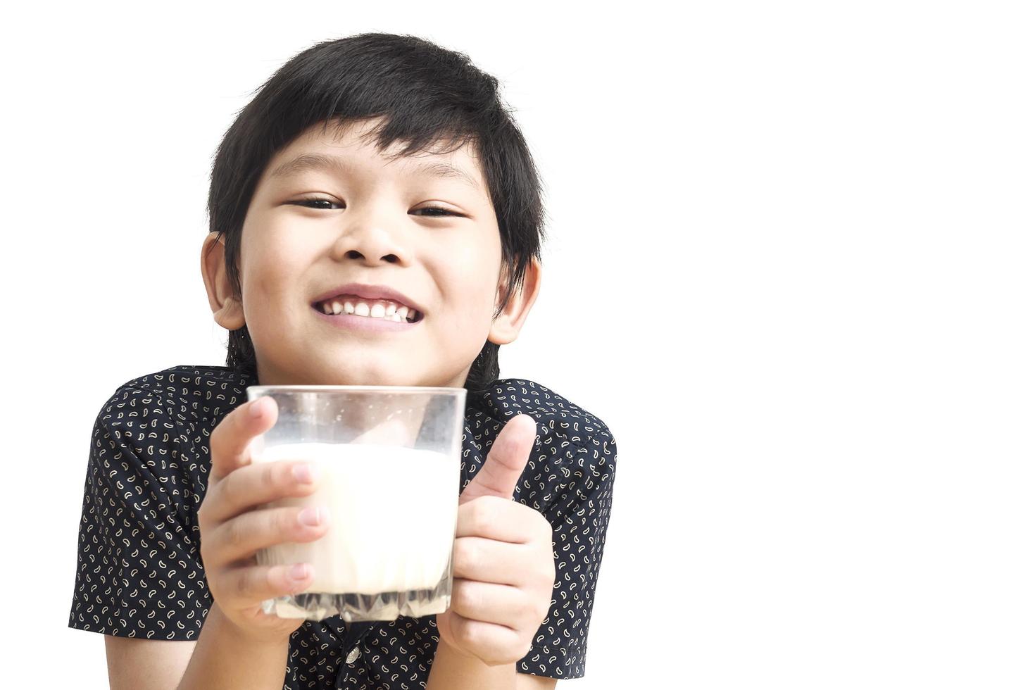 Asian boy is drinking a glass of milk over white background photo