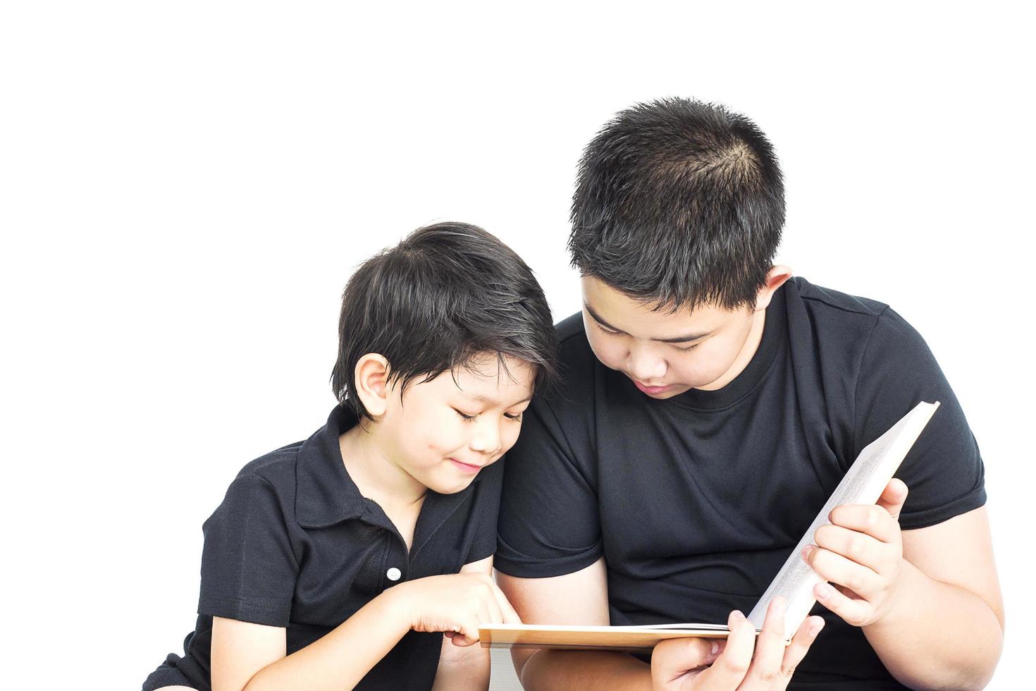 14 and 7 years Asian curious kids are happily reading book together isolated over white photo