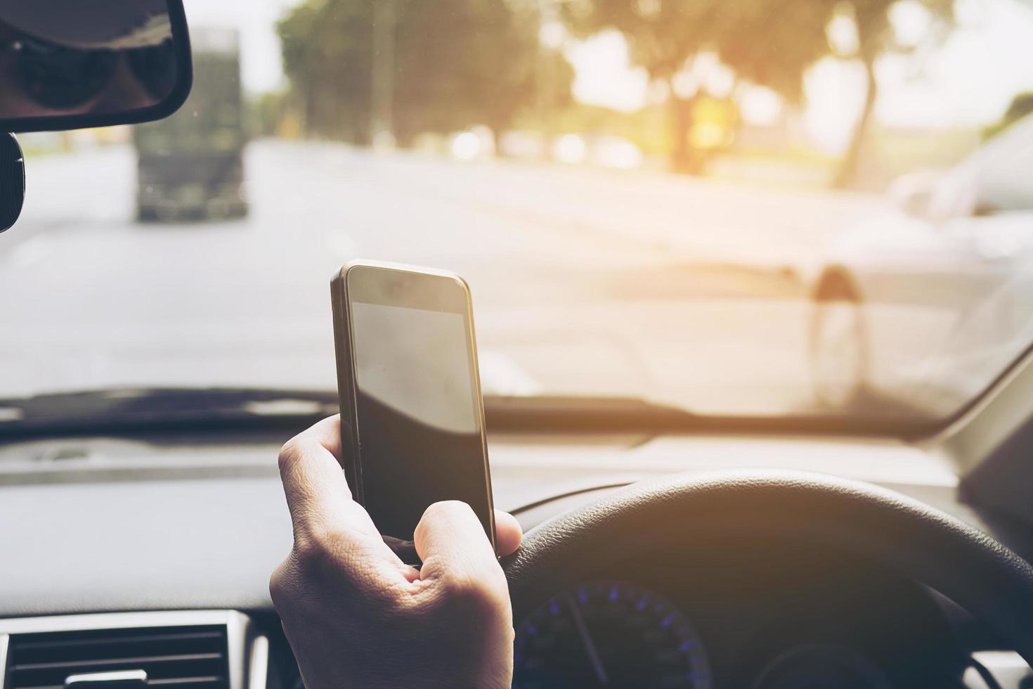 Close up of a man driving car dangerously while using mobile phone photo
